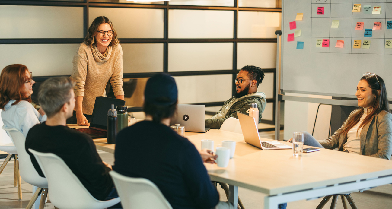 Group of startup team members brainstorming ideas around a table, with laptops.